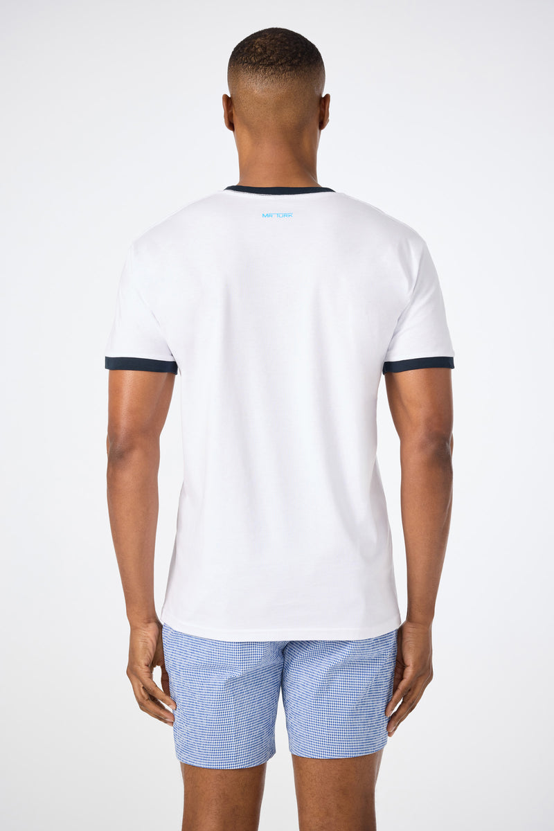 A man faces away from the camera, wearing the Short-Sleeve Crewneck T-Shirt - Pride in white with black trim and light blue checkered shorts, set against a plain white background.