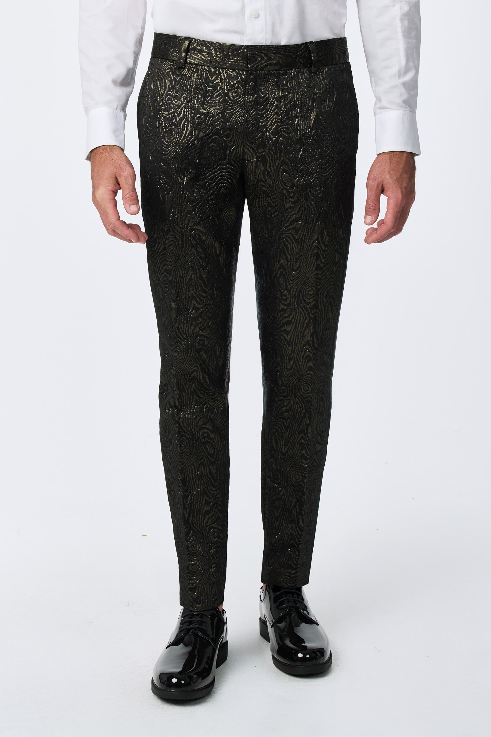 A man showcases only his lower body, wearing the Clyde Slim Trouser - Fette Swirl, paired with a white shirt and shiny black dress shoes against a plain white background.