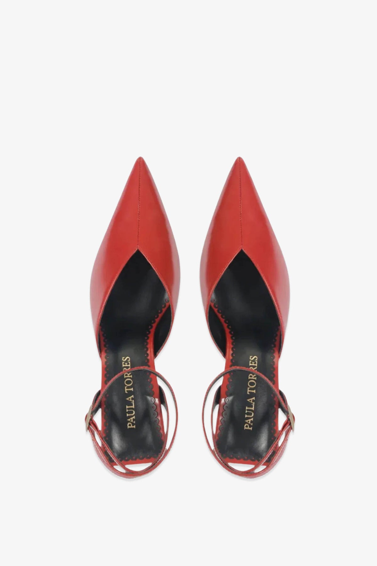 A pair of Paula Torres Cannes Pump red pointed-toe heels with ankle straps, viewed from above. The black insoles are embossed with PAULA TORRES in gold lettering.