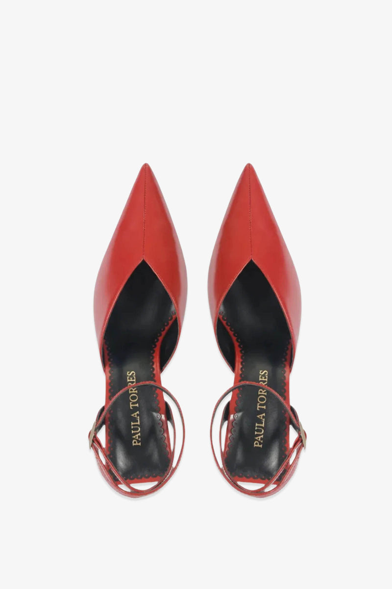 A pair of Paula Torres Cannes Pump red pointed-toe heels with ankle straps, viewed from above. The black insoles are embossed with PAULA TORRES in gold lettering.