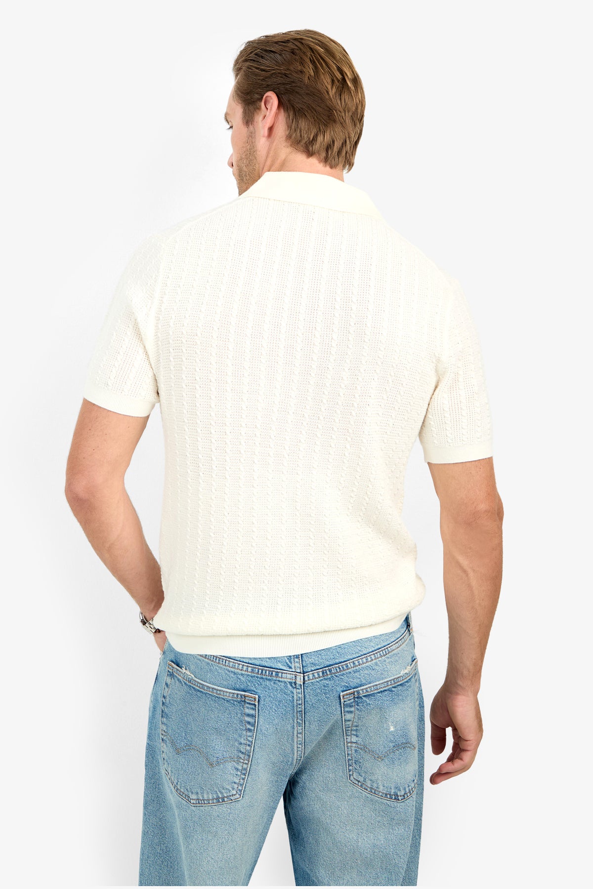 A man faces away, wearing the Asher Polo in off-white and light blue jeans against a plain white background.