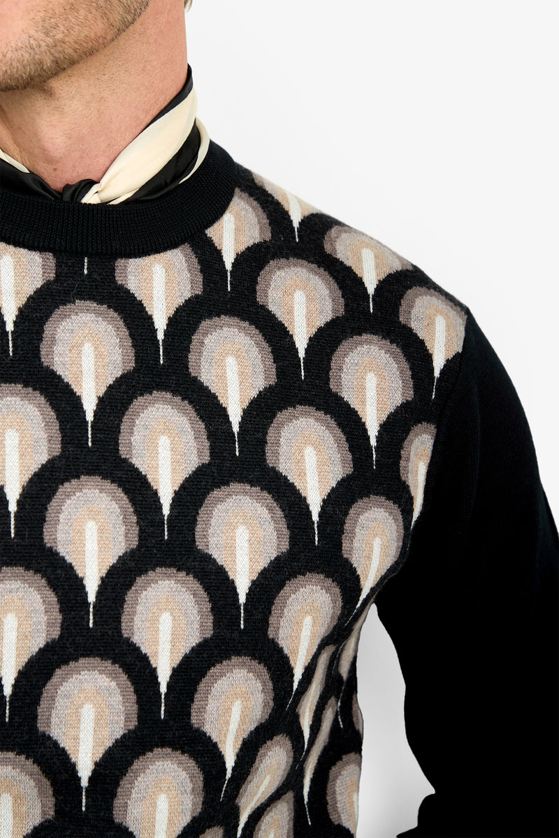 A person wears the Chrysler Sweater, featuring a geometric fan-shaped pattern in black, beige, and cream. The image focuses on the upper torso and neck against a white background.