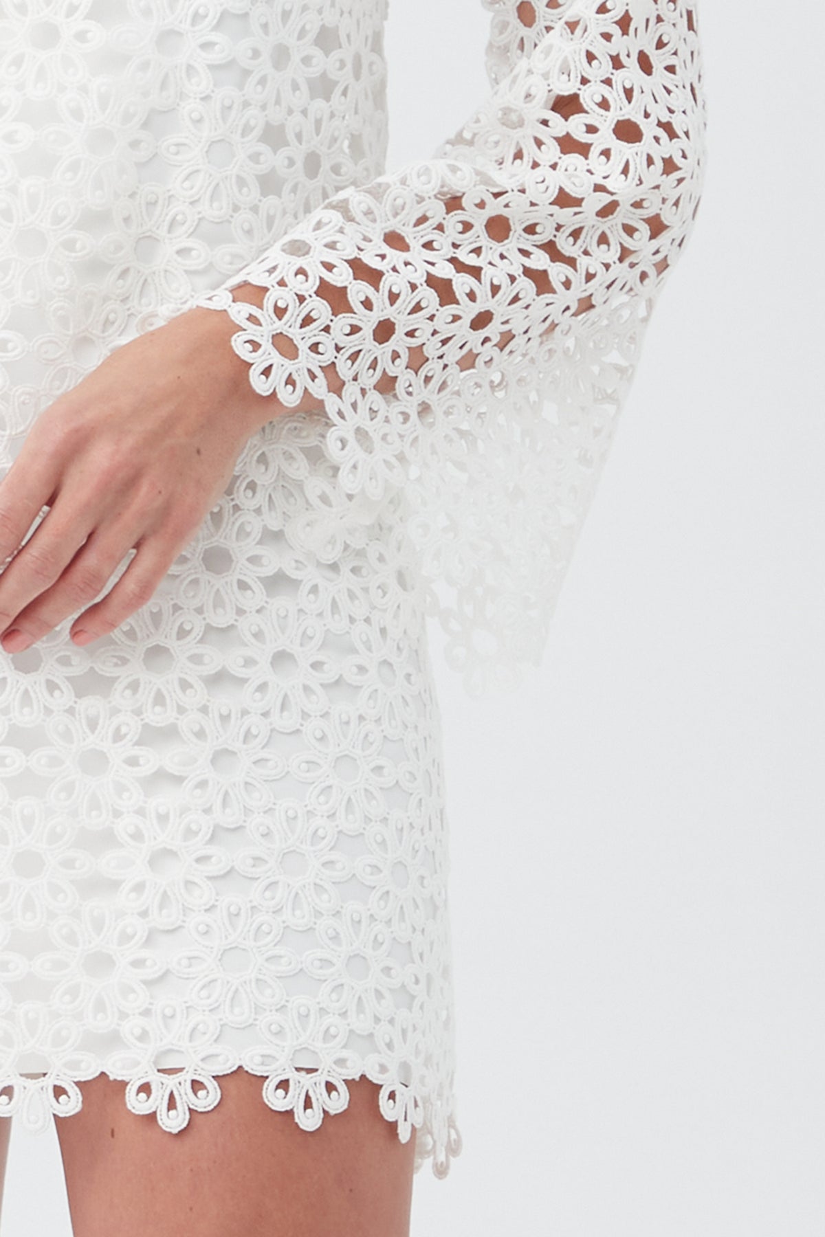 A woman models the Women's Chateau Lace Long Sleeve V-Neck Swim Cover-Up Dress with floral lace, bell sleeves, and scalloped edges—shown from torso to lower face against a plain background.