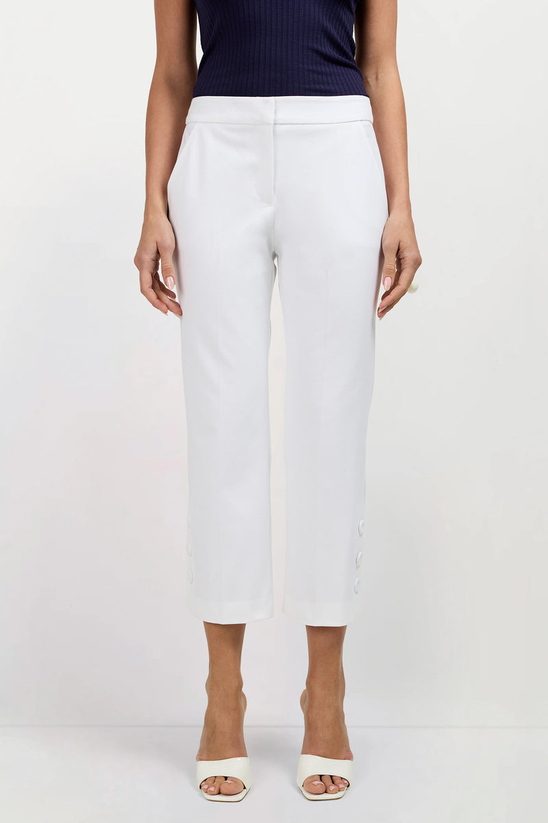 A person in Ore Button-Hem Cropped Pants, styled with a dark sleeveless top and white open-toed heels, stands against a plain light background.
