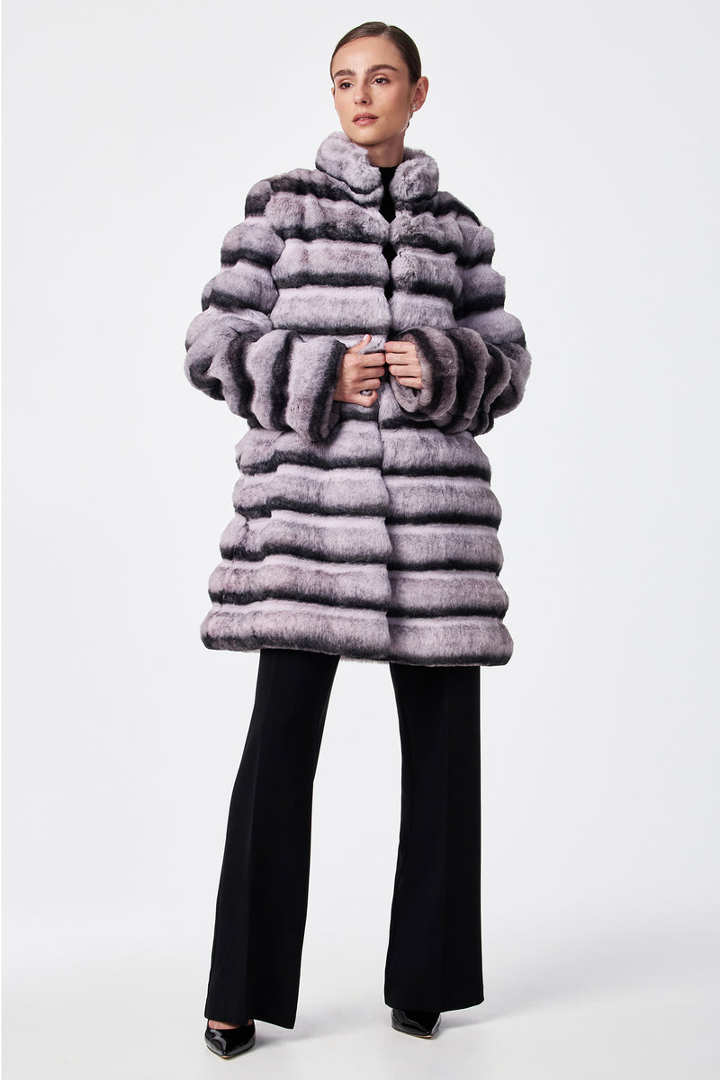A woman wears the Mikel 2 Faux Fur Mid-Length Coat with black wide-leg pants and black shoes, standing against a plain white background.