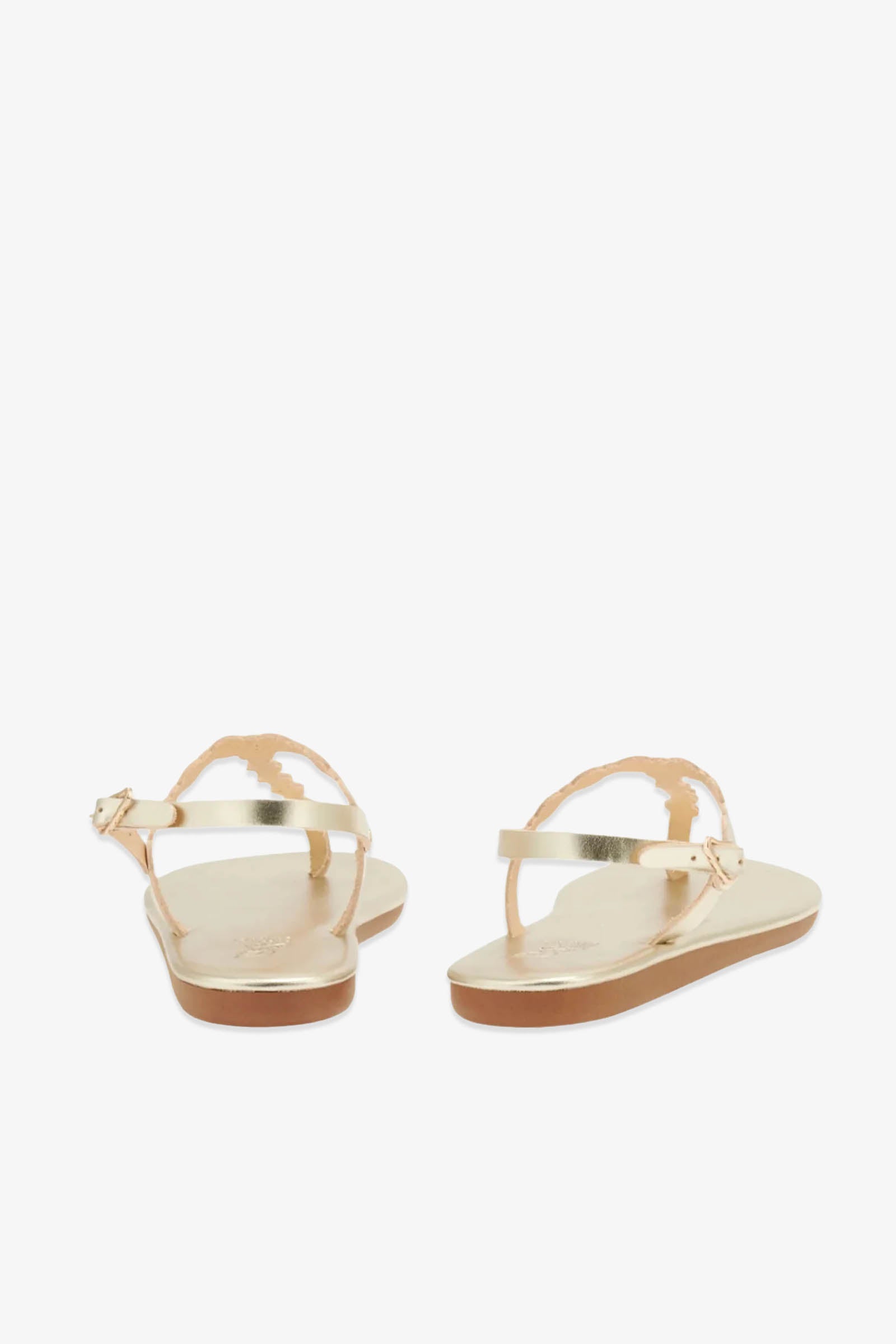 The Ancient Greek Sandals Velos are gold leather sandals featuring ankle straps and scalloped edges, inspired by ancient Greek designs; they are shown from the back against a white background.