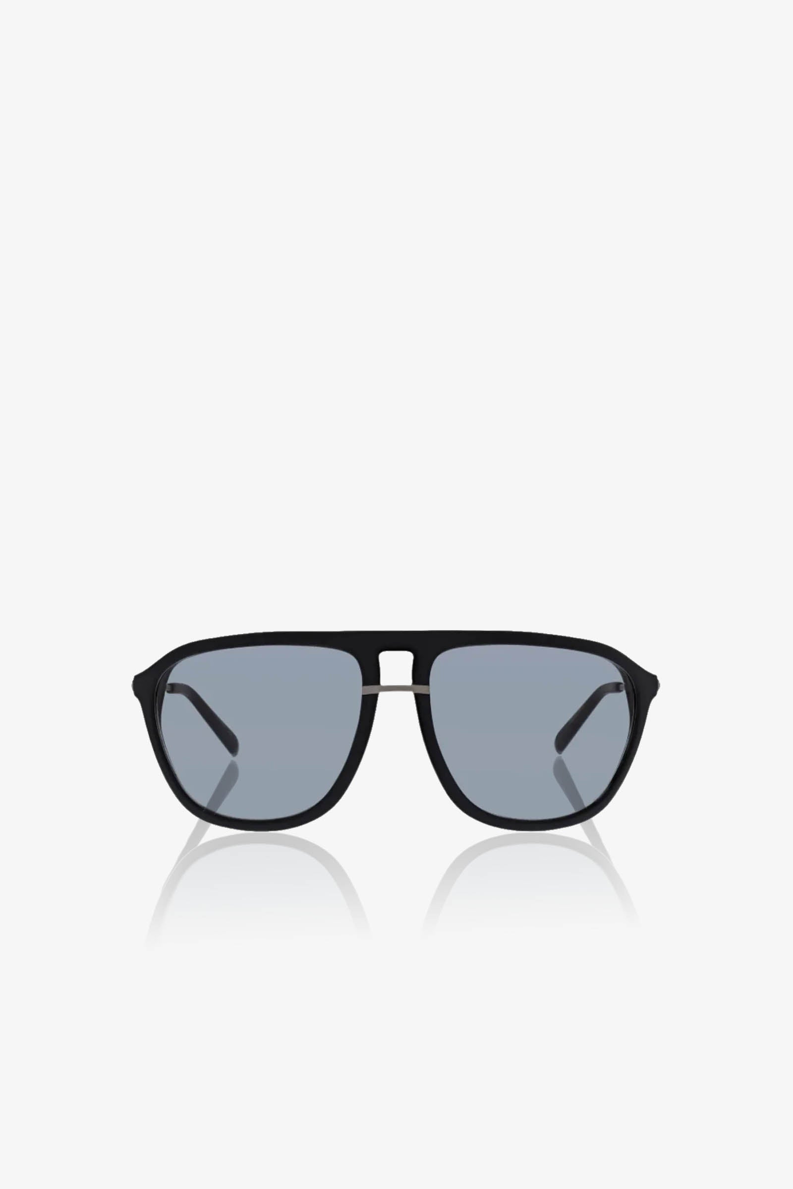 The Stern Sunglass features black aviator frames with oversized blue tinted lenses, showcased against a white background. Combining style and comfort, these sunglasses provide reliable UV protection.