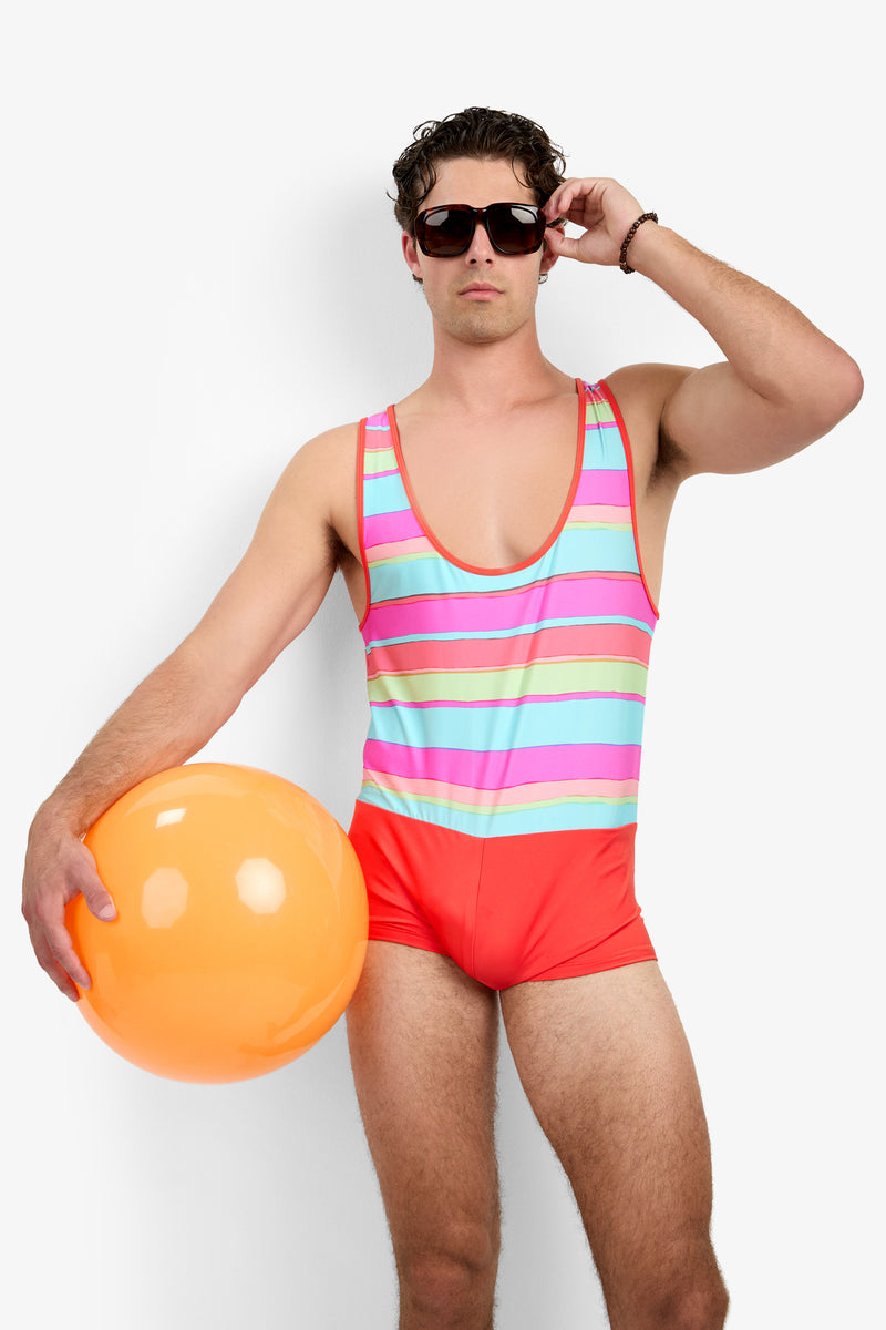 A man wearing sunglasses and the Sunset Beach Wetsuit - Sol Stripe poses with an orange beach ball against a plain white background.