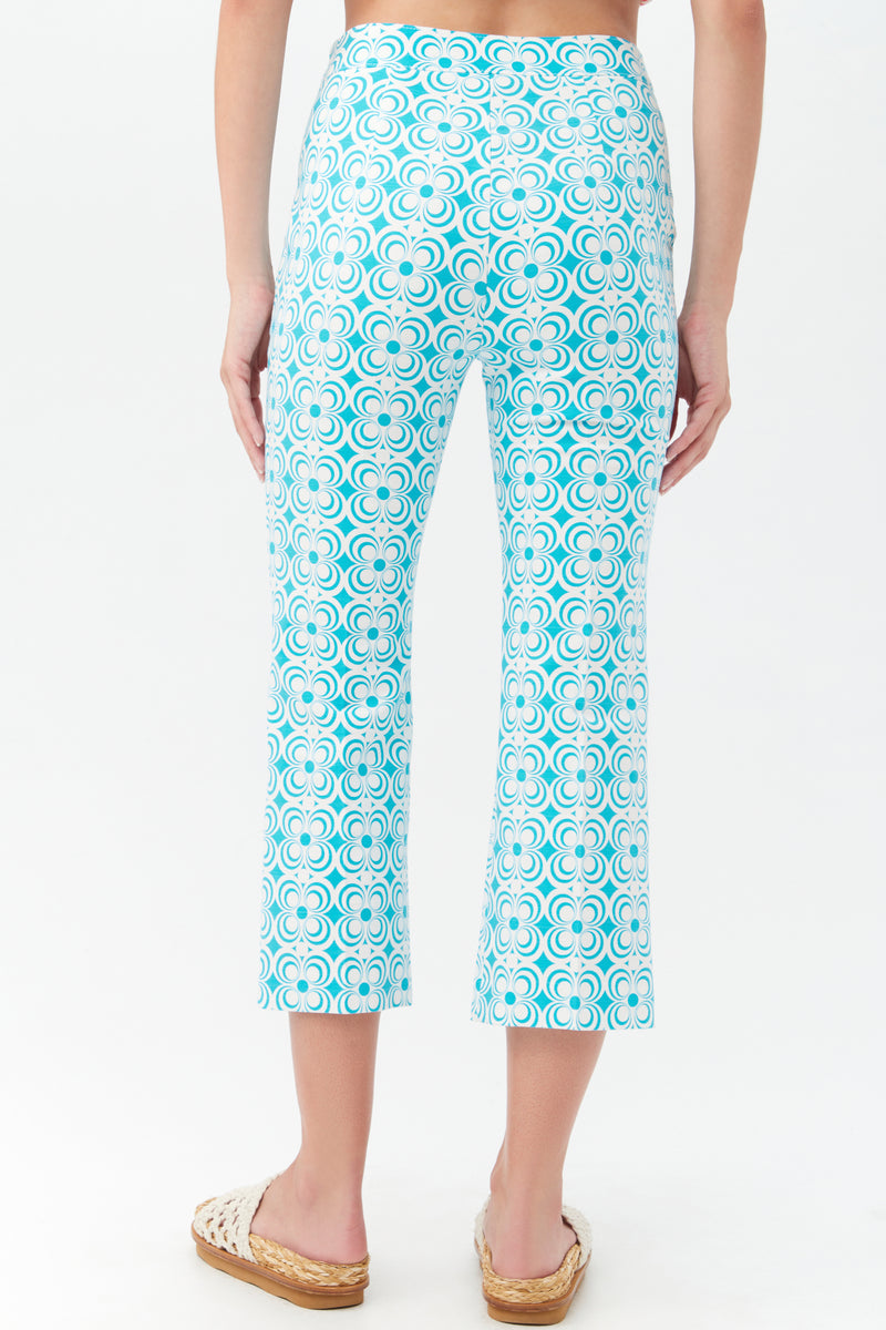 A person stands facing away, wearing the Flaire 2 Pant in a light blue and white pattern with woven beige espadrille sandals, set against a plain white background.