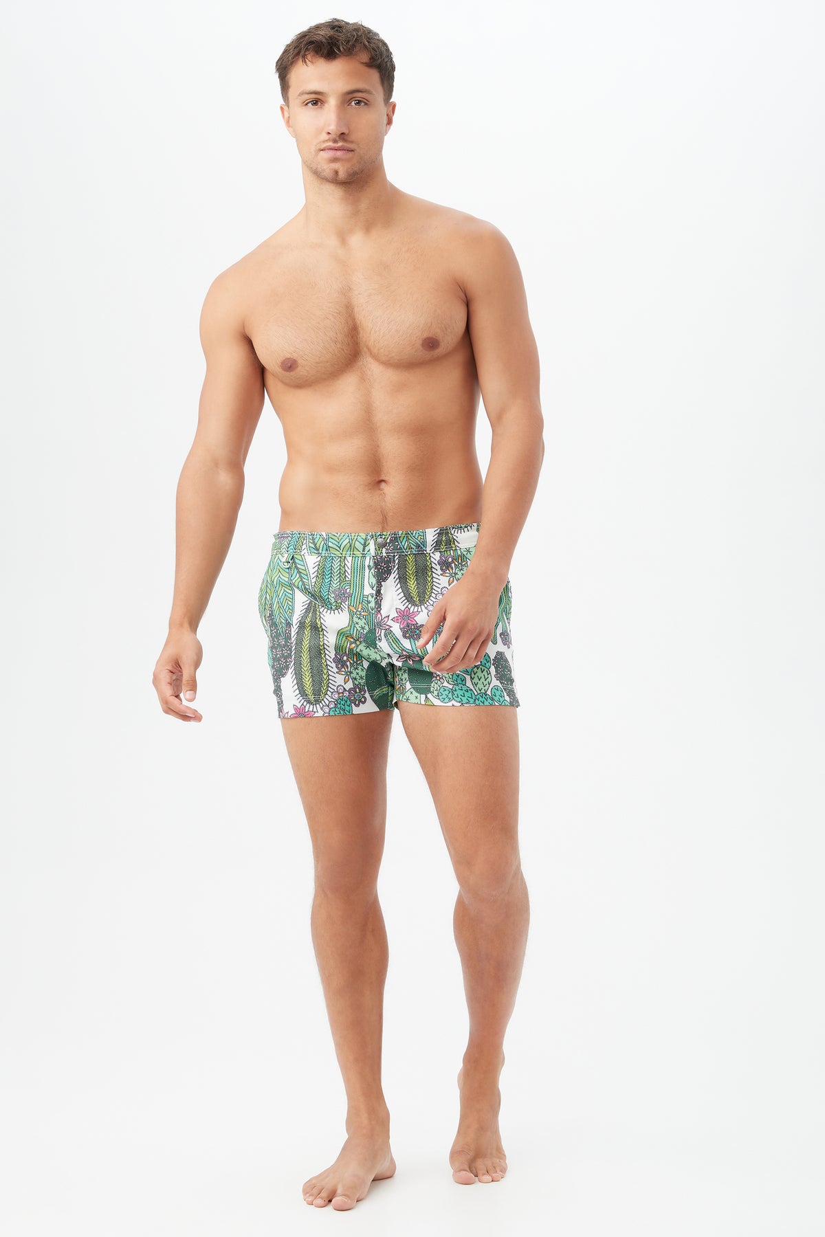 A shirtless man with short brown hair stands barefoot against a white background, wearing the Chico Swim Trunk - Cacti Swim Woven. He faces forward with a relaxed expression and posture.