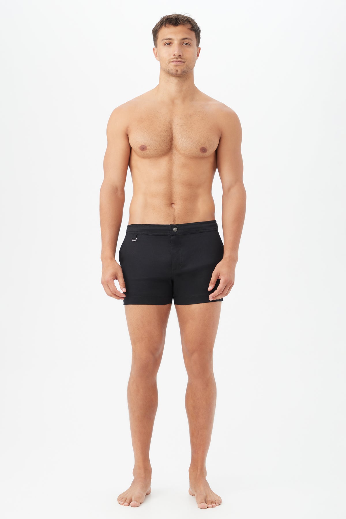 A man with short brown hair stands barefoot against a plain white background, facing forward in a neutral pose, wearing the Chico Swim Trunk - Metallic Swim Woven in black.