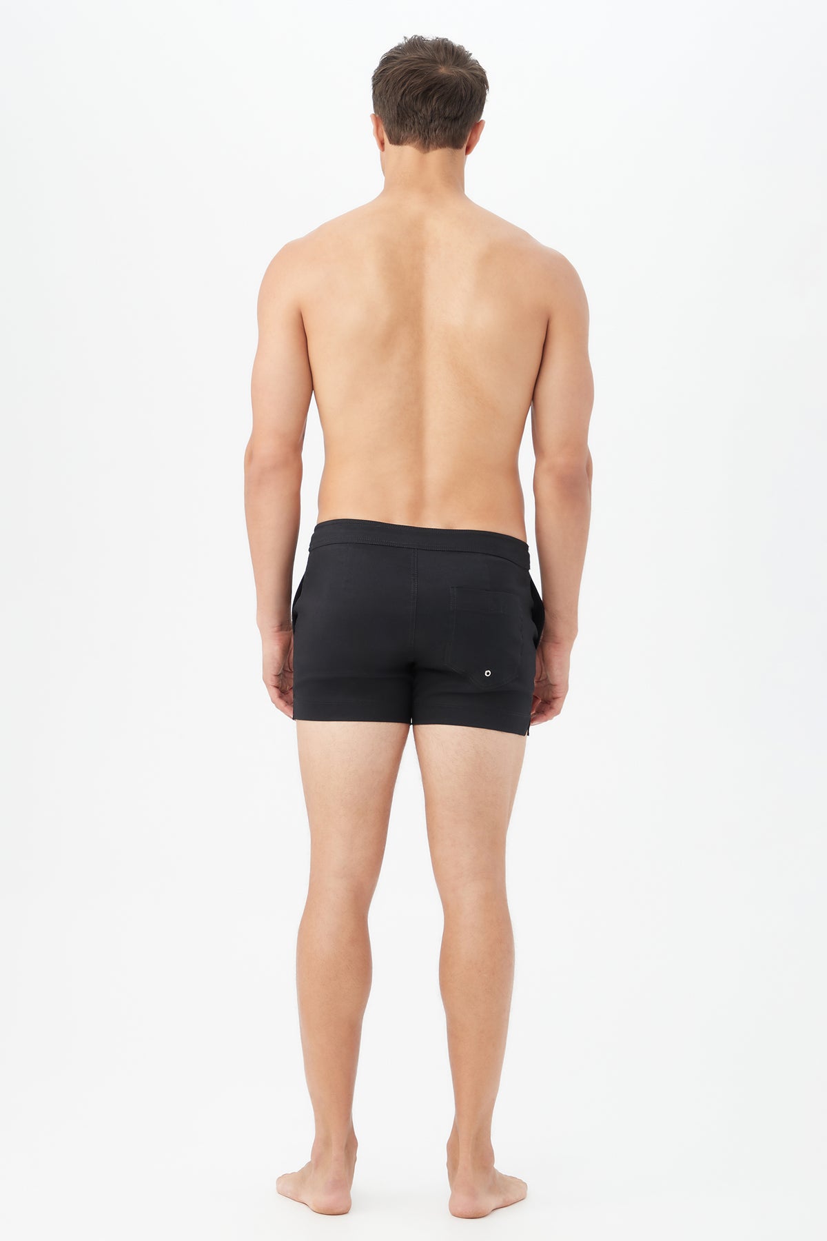A man stands barefoot with his back to the camera, wearing the Chico Swim Trunk - Metallic Swim Woven, against a plain white background.