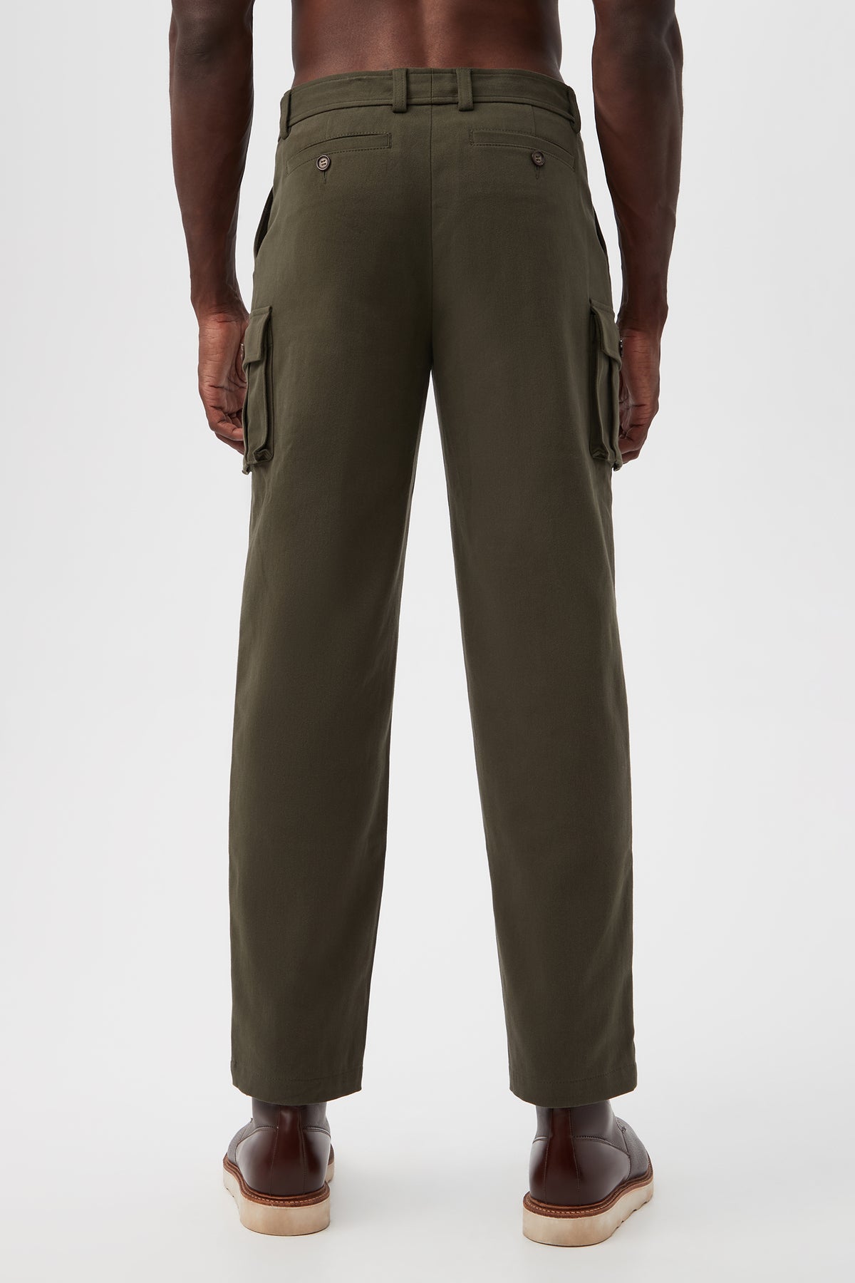 A man stands facing away in Lincoln Heights Cargo Trouser - Brushed Twill in olive green with side pockets and brown dress shoes, set against a plain white background.