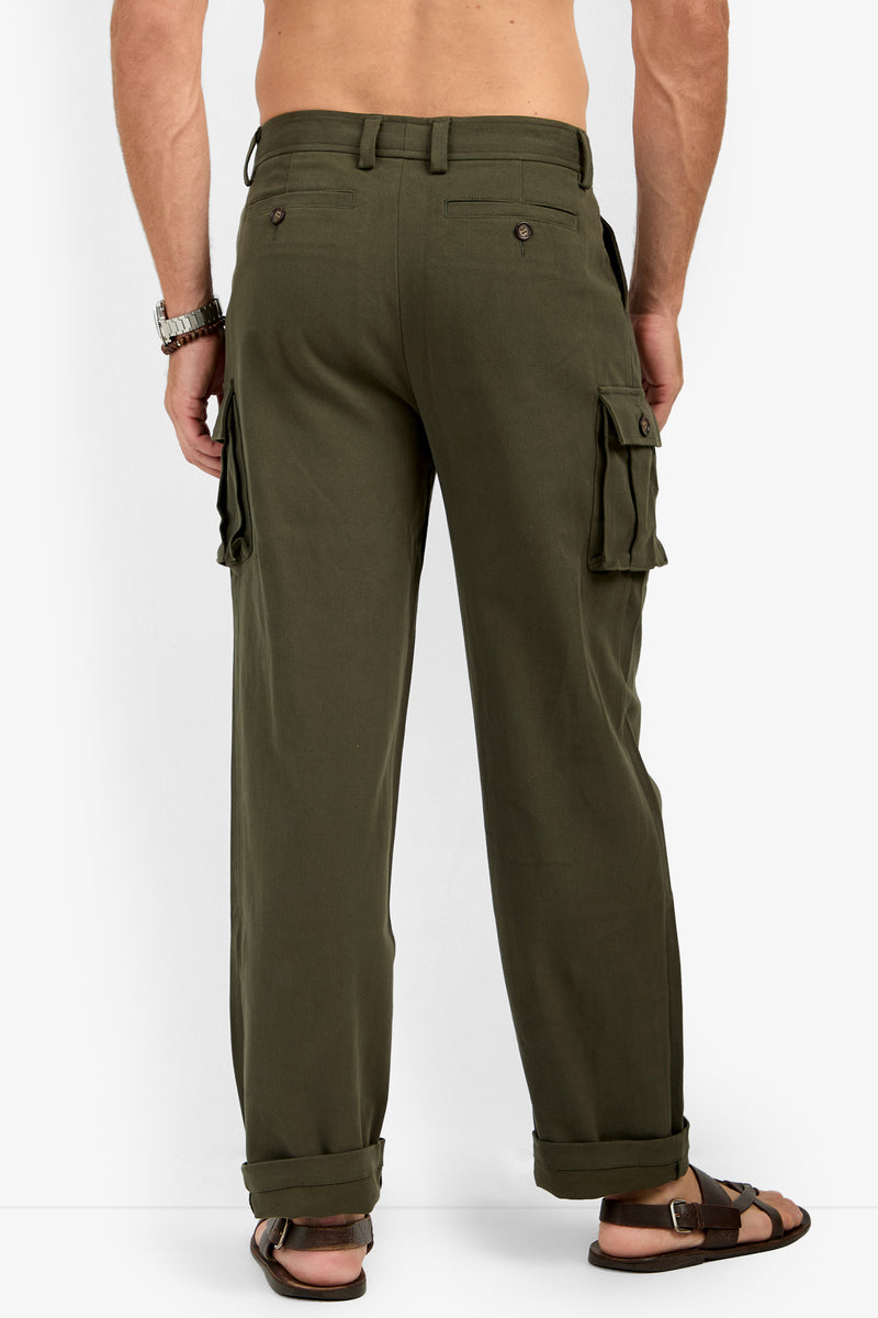 A man faces away, wearing Lincoln Heights Cargo Trouser - Brushed Twill in olive with rolled cuffs, side pockets, buttoned back pockets; styled with brown sandals, silver watch, and no shirt.