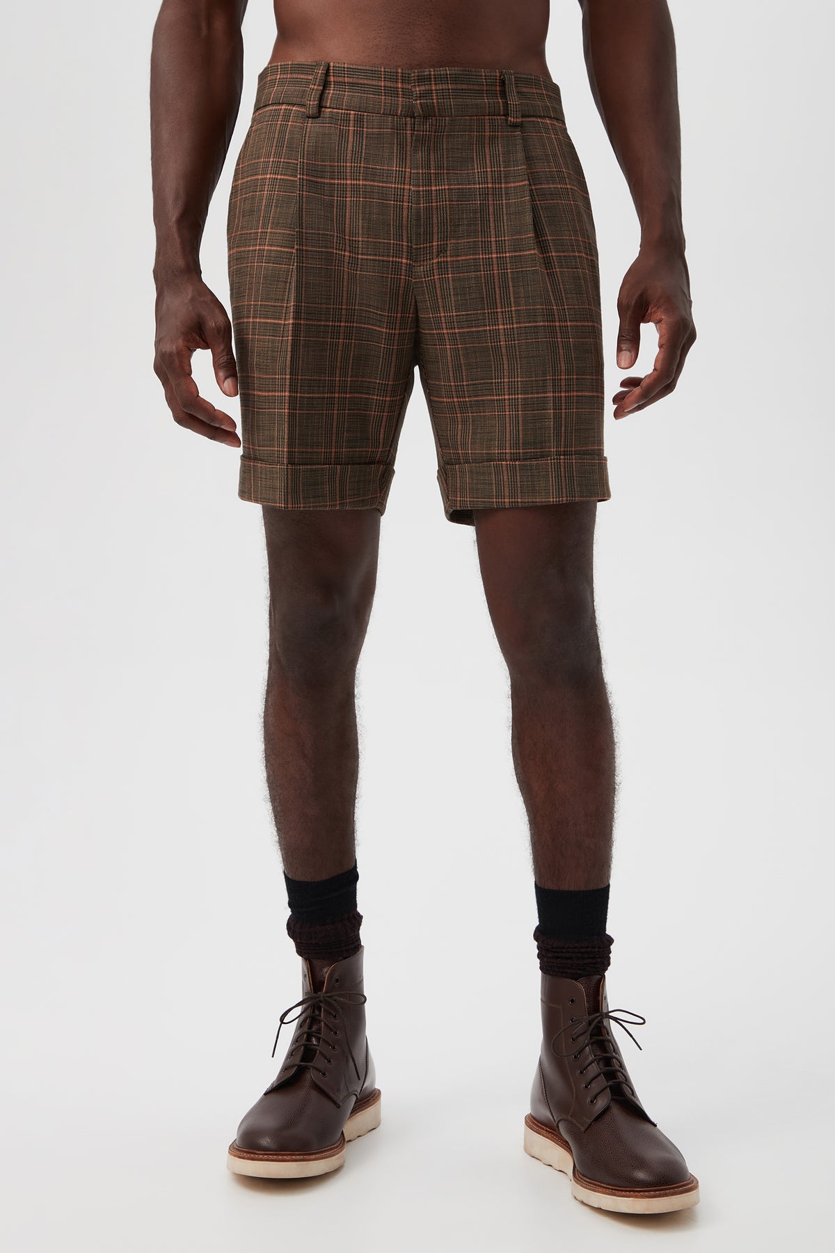 A person is shown from shoulders to feet wearing the Oliver 2 Short - Chaka Check Plaid in Multi, paired with black socks and brown lace-up boots, against a plain white background.