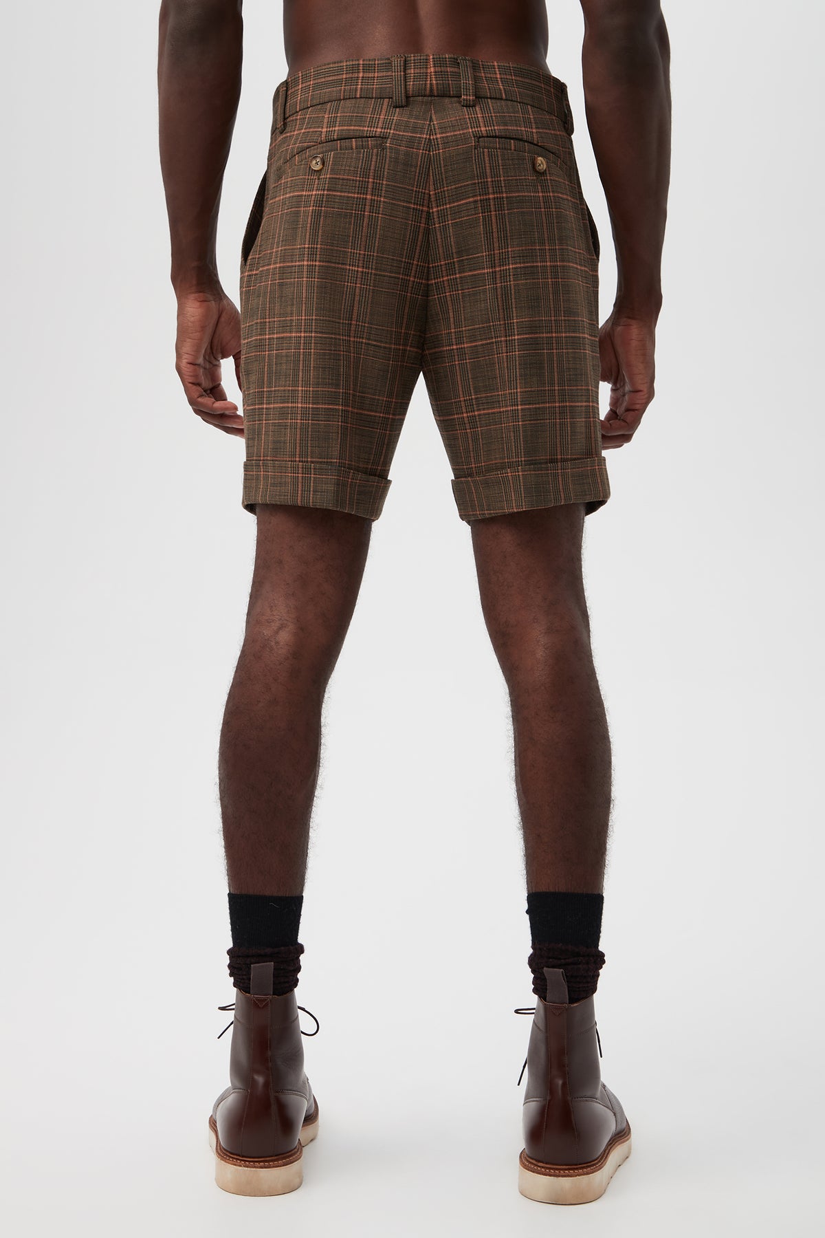 A person stands facing away from the camera against a plain white background, wearing the Oliver 2 Short - Chaka Check Plaid with black socks and brown leather boots.