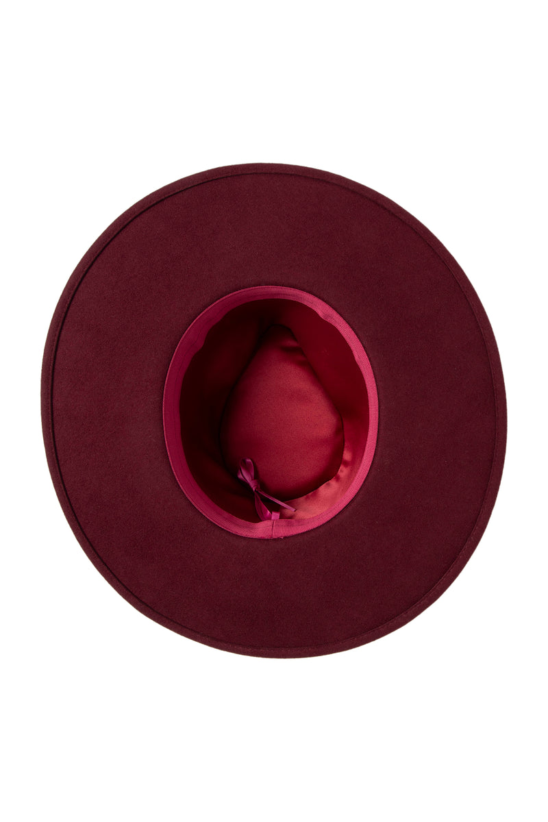 A top view of the Tt Josie Wool Felt Fedora, featuring a broad brim, burgundy wool felt, satin inner lining, and an interior ribbonâ€”a refined luxury accessory.