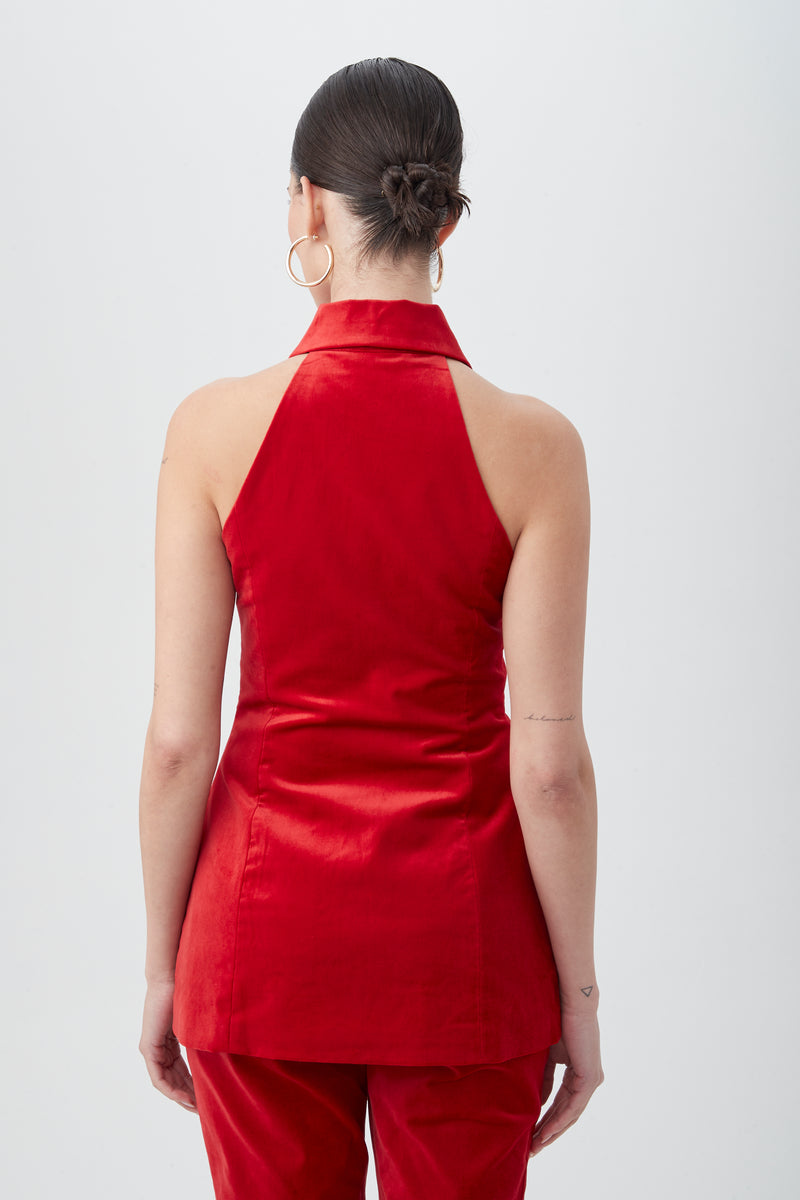 A woman with dark hair in a bun and large hoop earrings wears the Elainia Velveteen Sleeveless Tunic Top, styled from the back against a plain light background.