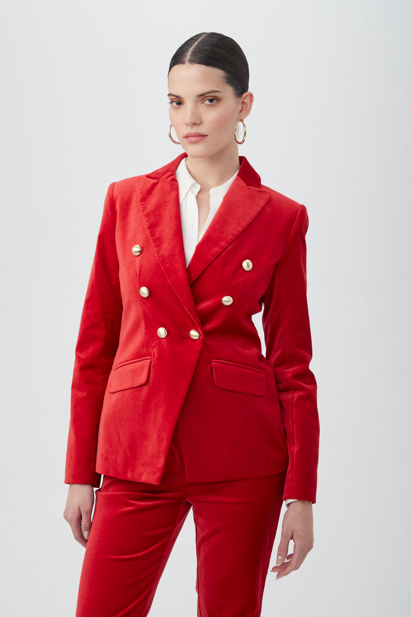 Wearing the Midlands Velveteen Blazer Jacket, a person in a bright red double-breasted suit with gold buttons and a white shirt stands against a plain light background, confidently facing the camera.