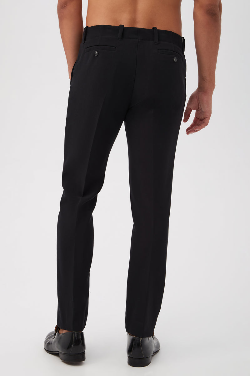 A person is shown from the back wearing the Alex Slim Trouser - Luxe Drape in black with black shoes, standing shirtless against a plain white background.