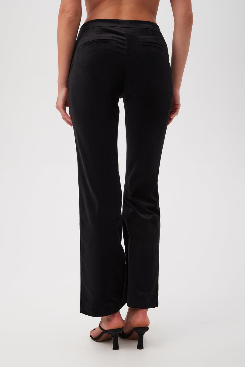 Someone is shown from the back against a plain white background wearing the Westport Velveteen Bootcut Pant in black, paired with black heeled sandals.