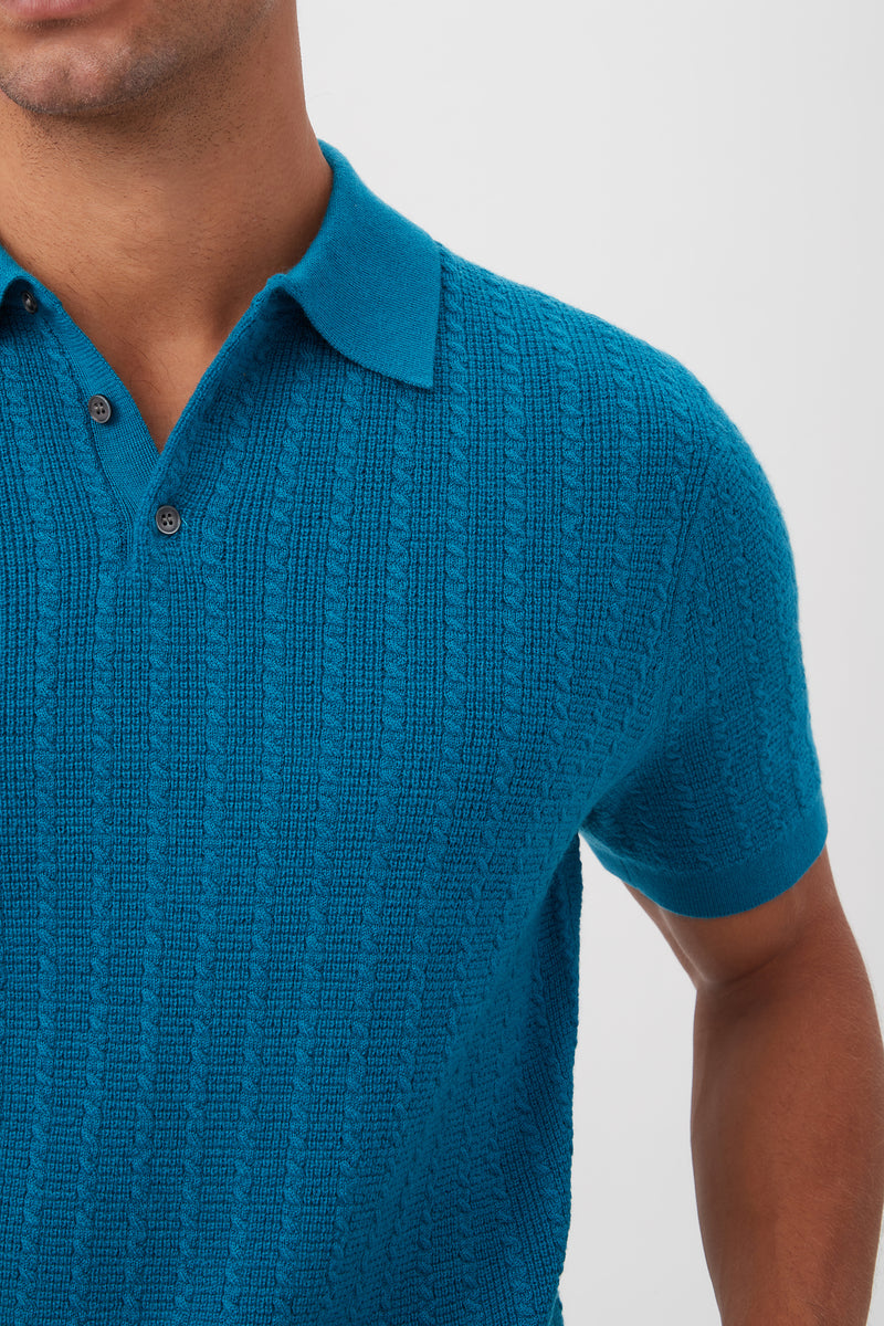 A person models the Asher Short-Sleeve Polo - Merino Wool in textured bright blue, featuring a collar and buttons, shown from shoulders to mid-torso against a plain light background.