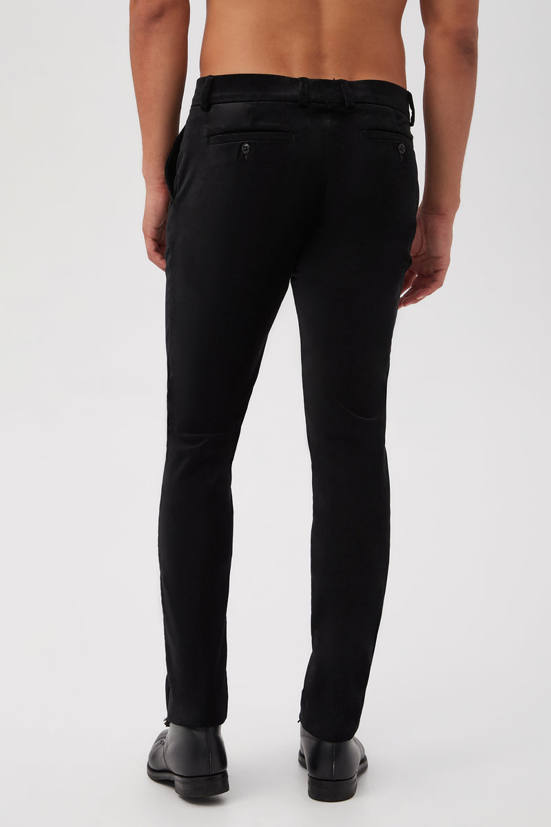 A shirtless person is shown from behind, wearing the Clyde Slim Trouser in Black Velveteen and black dress shoes against a plain white background.