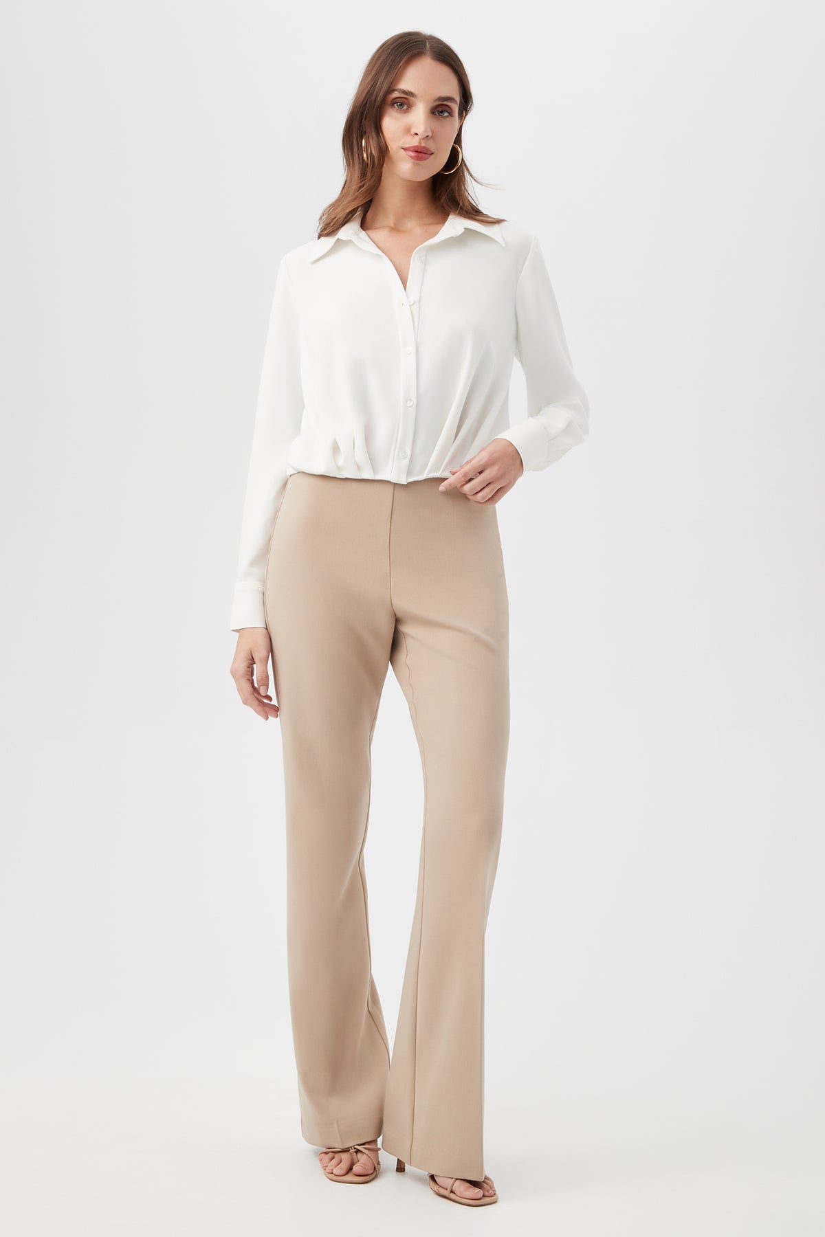 A woman with shoulder-length brown hair and a neutral expression stands against a white background wearing the Renlee Shirt, beige high-waisted wide-leg trousers, and open-toe heels.