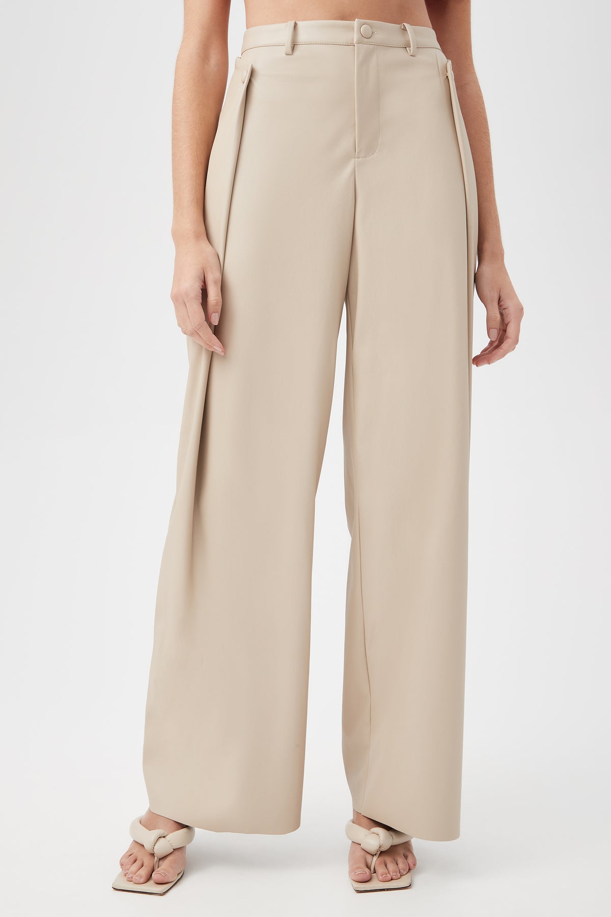 A person models the Bexley Pant in Chai—high-waisted, wide-leg trousers—paired with light sandals, standing against a plain white background. Only their lower torso and legs are visible.