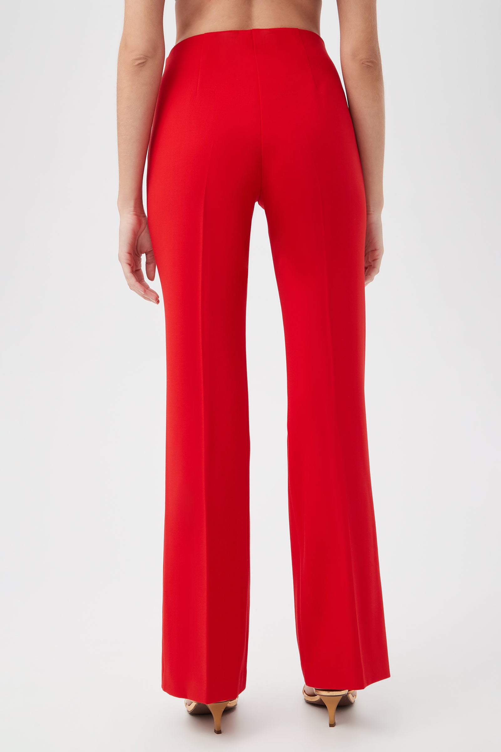 A person faces away from the camera, wearing Jacoba Slim-Fit Stretch Bootcut Pants in bright red with beige high-heeled shoes, set against a plain white background.