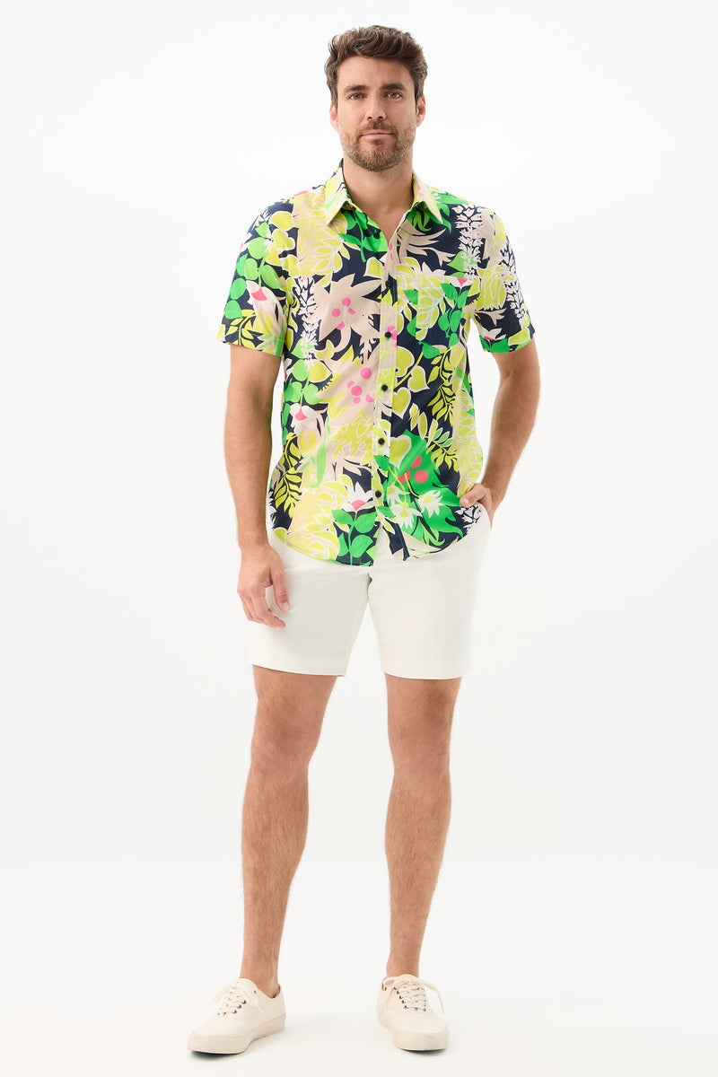 A man stands against a white background wearing the Slim Jim Short-Sleeve Shirt, paired with white shorts and sneakers, his left hand in his pocket and a relaxed expression.