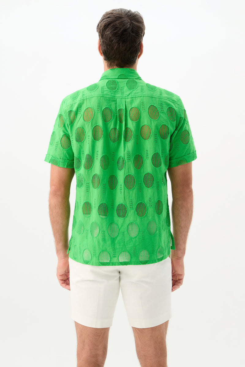 A man faces away, wearing the Branson Shirt - Tennis Eyelet in bright green with circular cutout patterns and white shorts. The background is plain white.