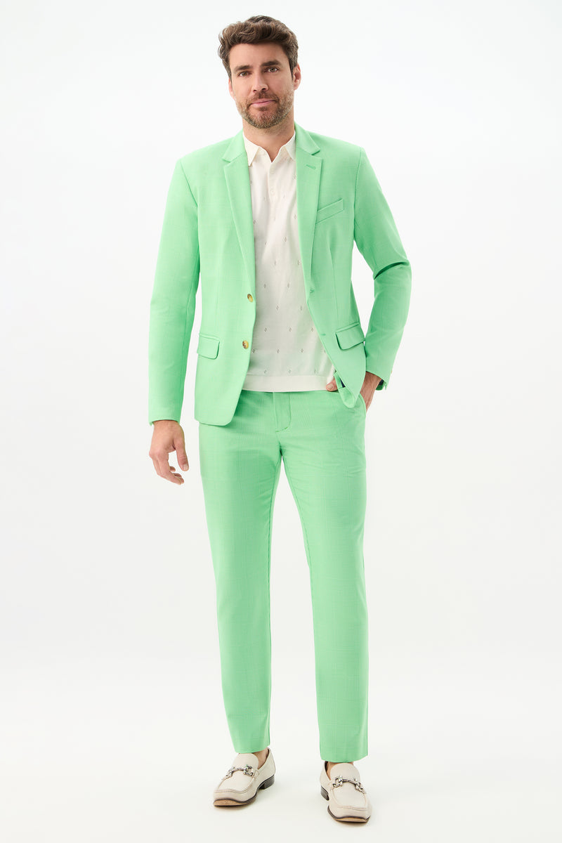 A man stands facing forward, wearing the Thurston Blazer - Game Time Glen Plaid with a white shirt and white shoes. The plain white background highlights the pastel green hue of the blazer.