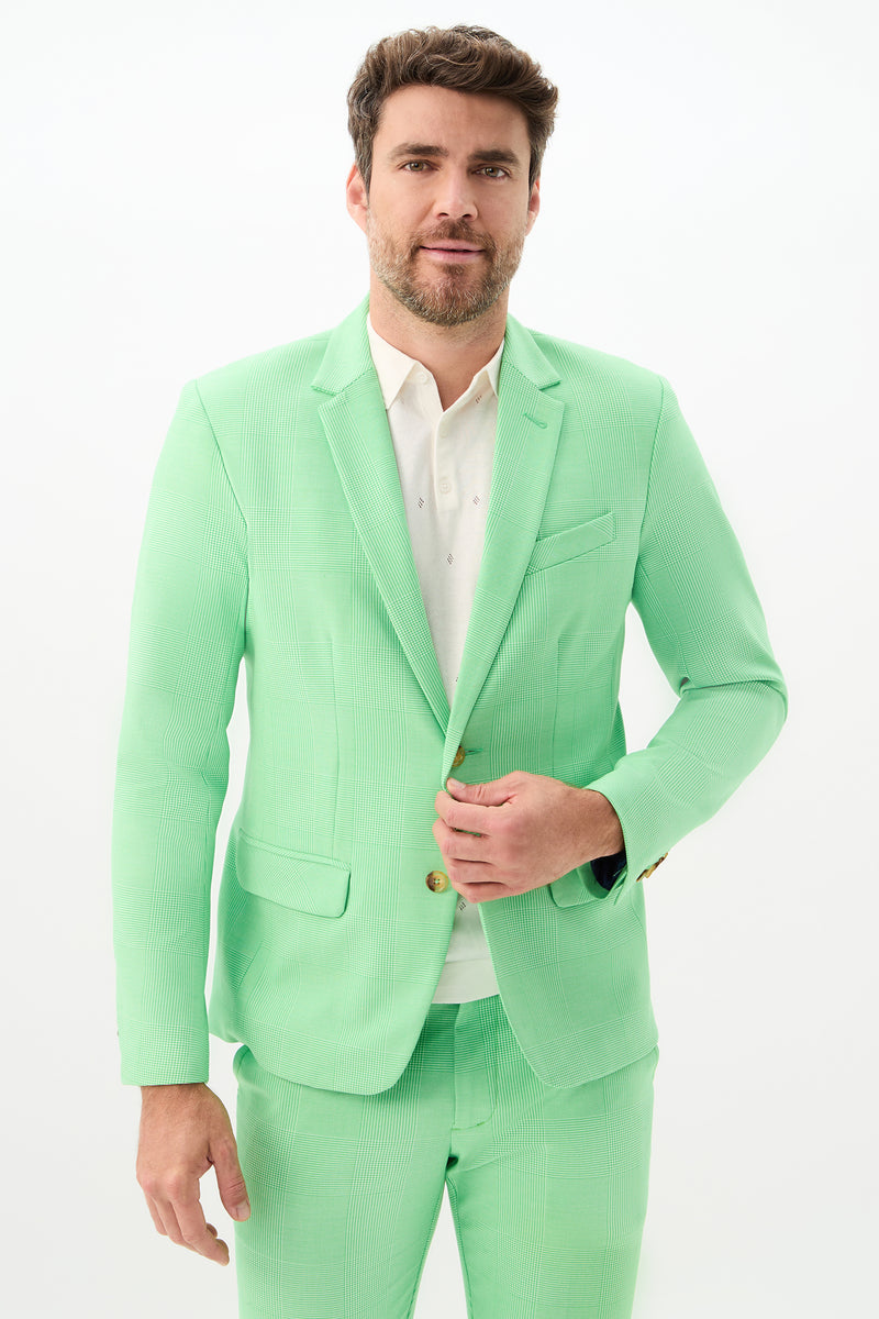 A man with short brown hair and a beard is wearing the Thurston Blazer - Game Time Glen Plaid in Grass Court Green/Whitewash over a white shirt, standing against a plain white background and buttoning his jacket.