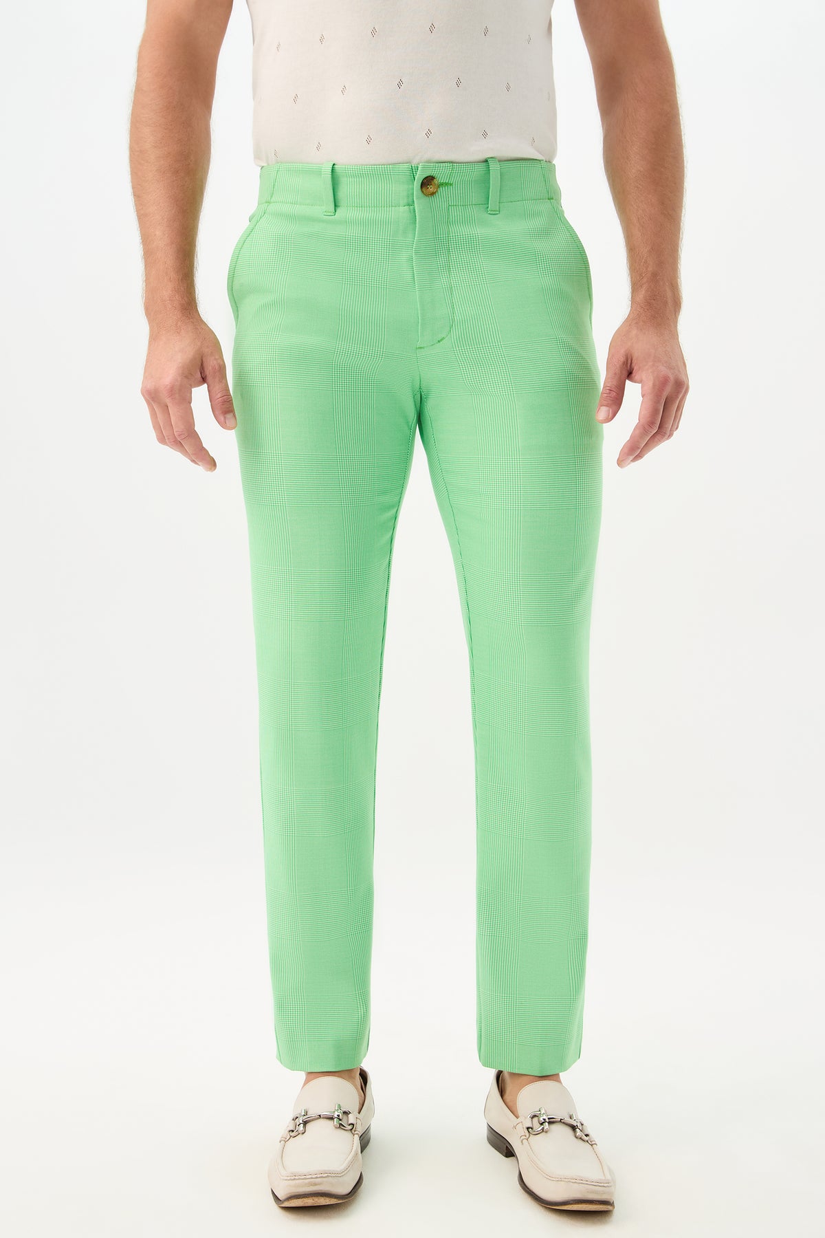 A man wearing the Alex Slim Trouser in Grass Court Green/Whitewash stands against a white background. The photo is cropped at the torso, highlighting the pants and his light-colored loafers.