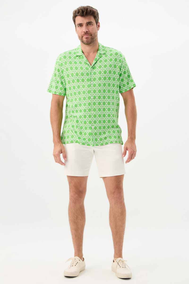 A man faces forward wearing the Felix Short-Sleeve Knit Shirt in Billie Jean, paired with white shorts and white sneakers, set against a plain white background.