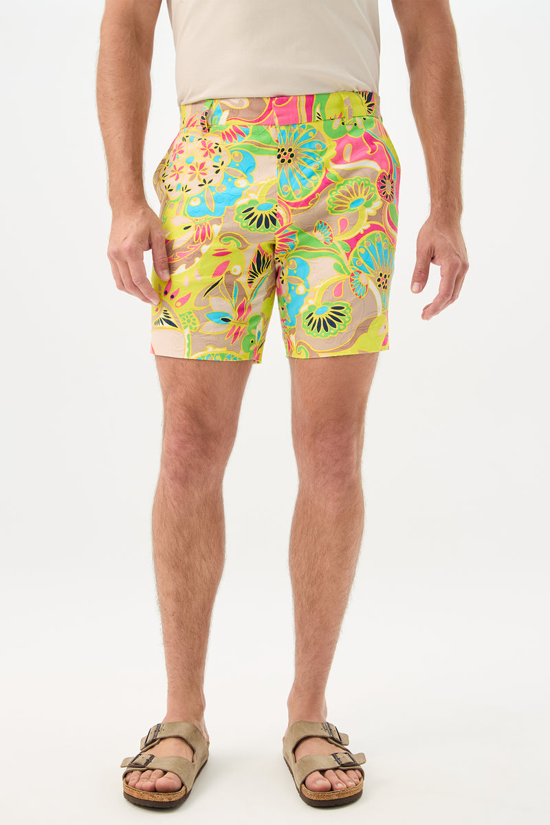 A person wearing a cream t-shirt, Lawrence Short in Venus (a colorful floral print), and tan sandals, standing against a plain white background.