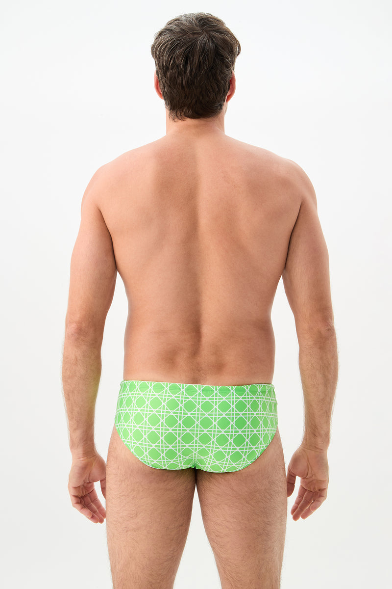 A man, shirtless and facing away from the camera against a plain light background, is wearing the Bondi Swim Brief - Billie Jean in a light green patterned design.