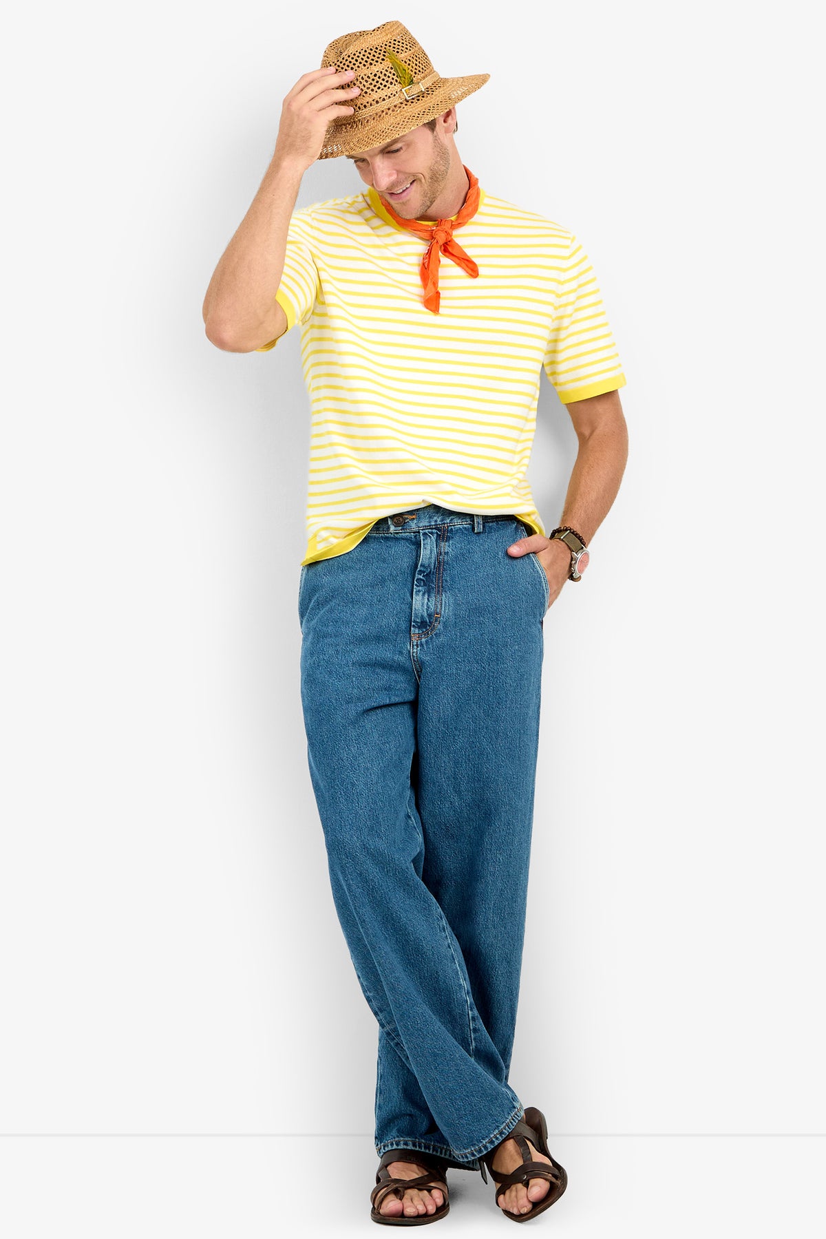 Man wearing a straw hat, red neckerchief, blue jeans, sandals, and a Giovanni Stripe Short-Sleeve Pullover stands casually, smiling and tipping his hat.