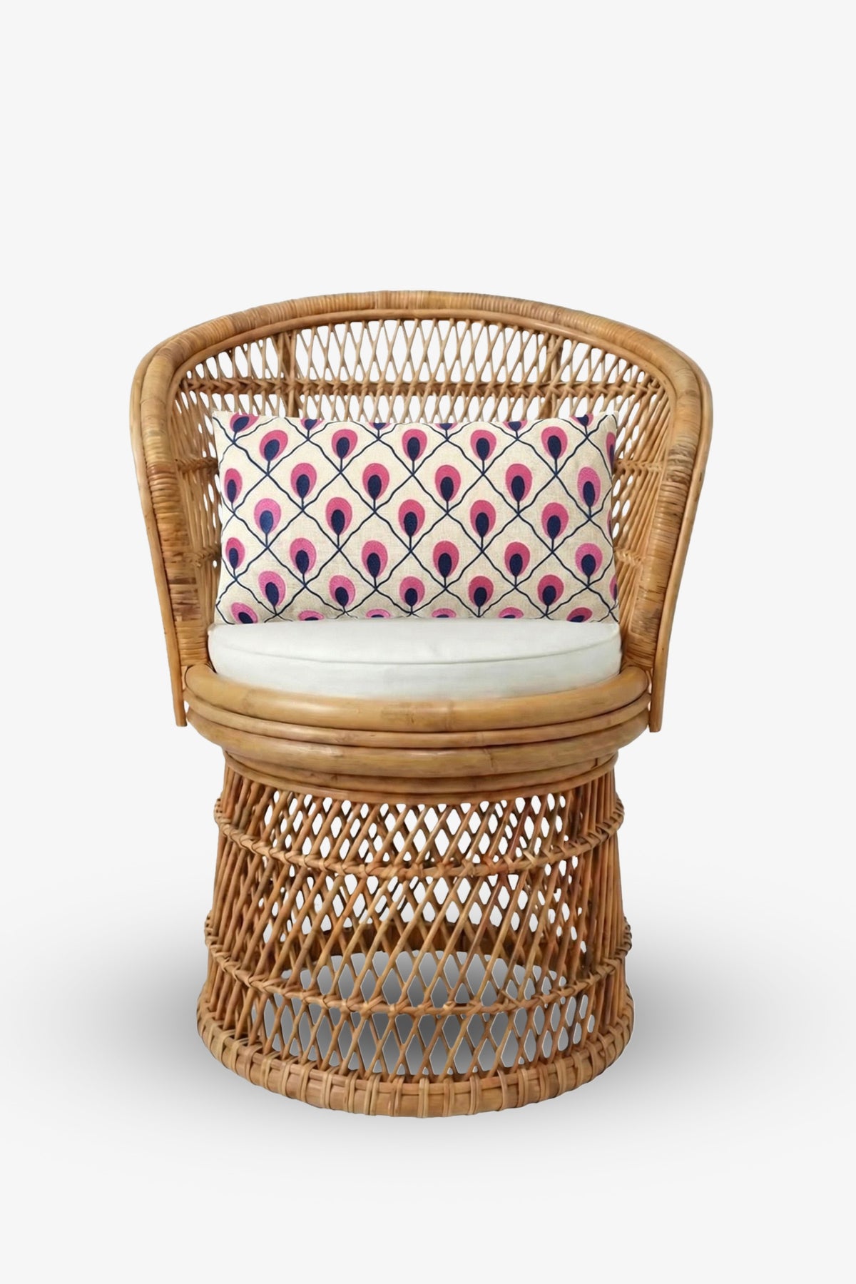 A round rattan chair with a white cushion is accented by the Embroidered Lumbar Pillow, which features a pink and navy blue peacock feather pattern, set against a plain white background.