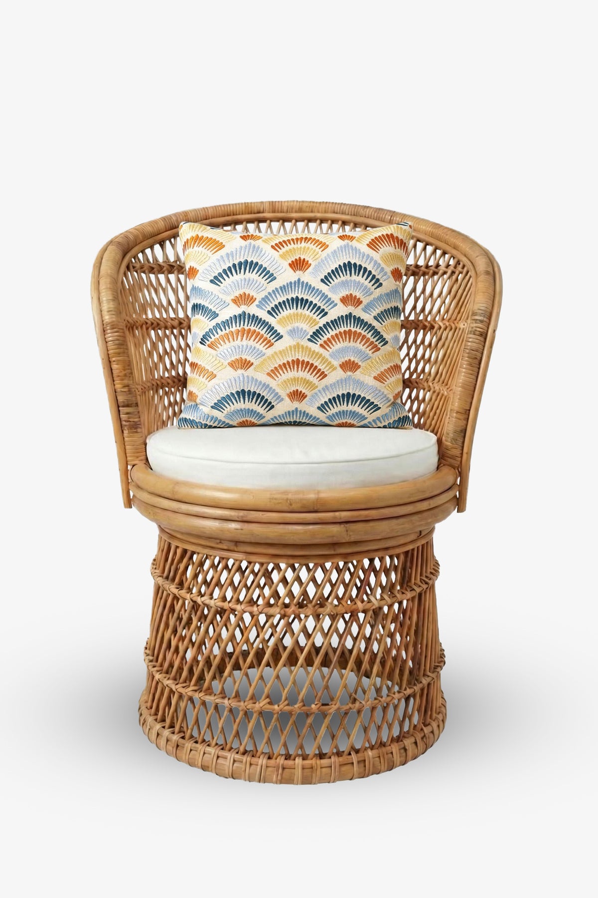 A round wicker chair with a white cushion and the Pasadena Embroidered Square Pillow, which features a scalloped pattern in blue, orange, and yellow tones, set against a plain white background.