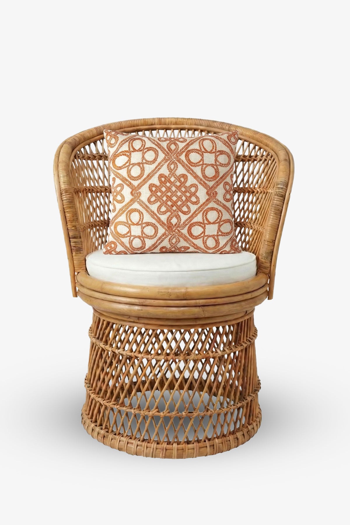 A round rattan chair with a woven base, white seat cushion, and the Costa Mesa Embroidered Square Pillow featuring an orange geometric pattern.