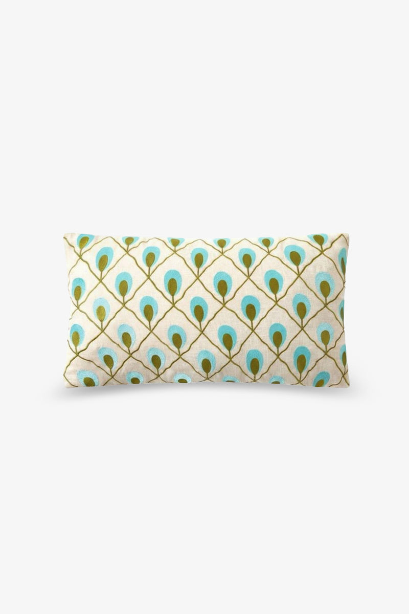 The Roseville Embroidered Lumbar Pillow features a rectangular shape with a repeating pattern of stylized turquoise and gold peacock feathers on a white background.
