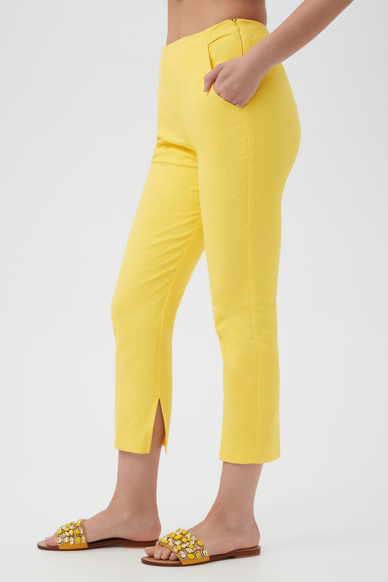 A person wears Pop Slim-Leg Stretch Pants in bright yellow with front hem slits and embellished yellow slide sandals, standing against a plain white background.