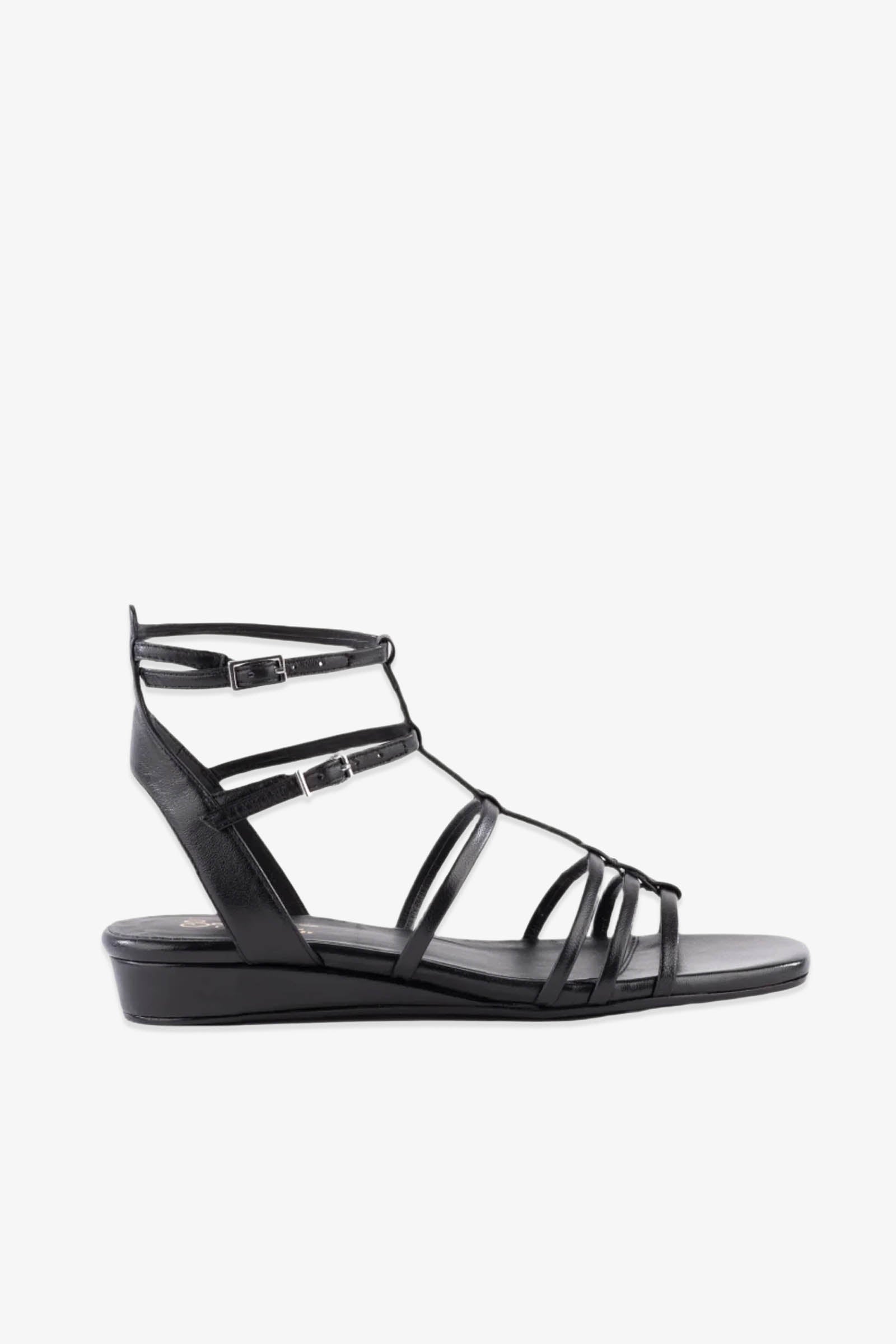 Luxurious Wedge Sandal - Black Leather features multiple thin black straps across the foot, two ankle buckles, a closed heel, and a subtle wedge heel. Displayed in profile against a white background.
