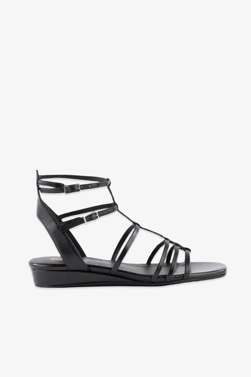 Luxurious Wedge Sandal - Black Leather features multiple thin black straps across the foot, two ankle buckles, a closed heel, and a subtle wedge heel. Displayed in profile against a white background.