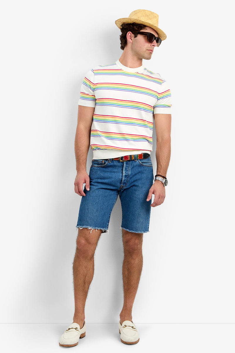 A man in the Carlo Short-Sleeve Crewneck - Pride, denim shorts, straw hat, sunglasses, belt, wristwatch, and white loafers stands against a white background.