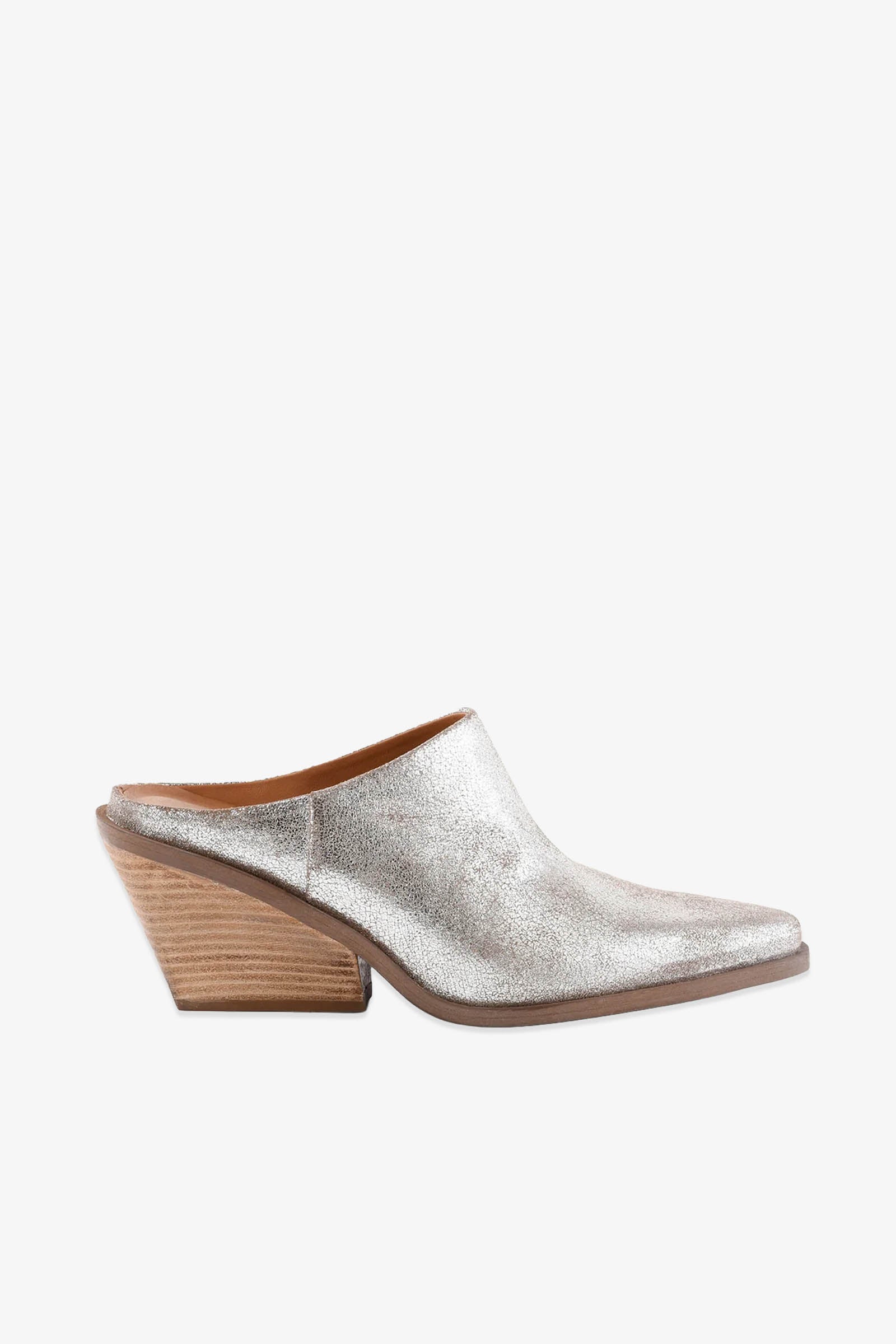 The Morning Joe Mule is a silver metallic mule shoe featuring a pointed toe and a chunky, angled wooden heel, displayed in profile against a plain white background.