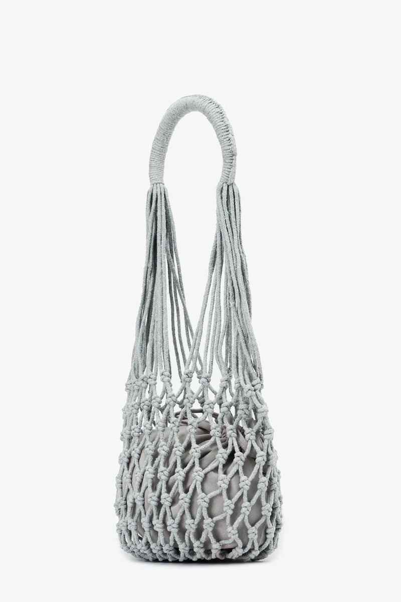 The Nannacay Kim Woven Bag, featuring a light gray woven net design with thick handles and an inner fabric pouch, is displayed upright against a plain white background.
