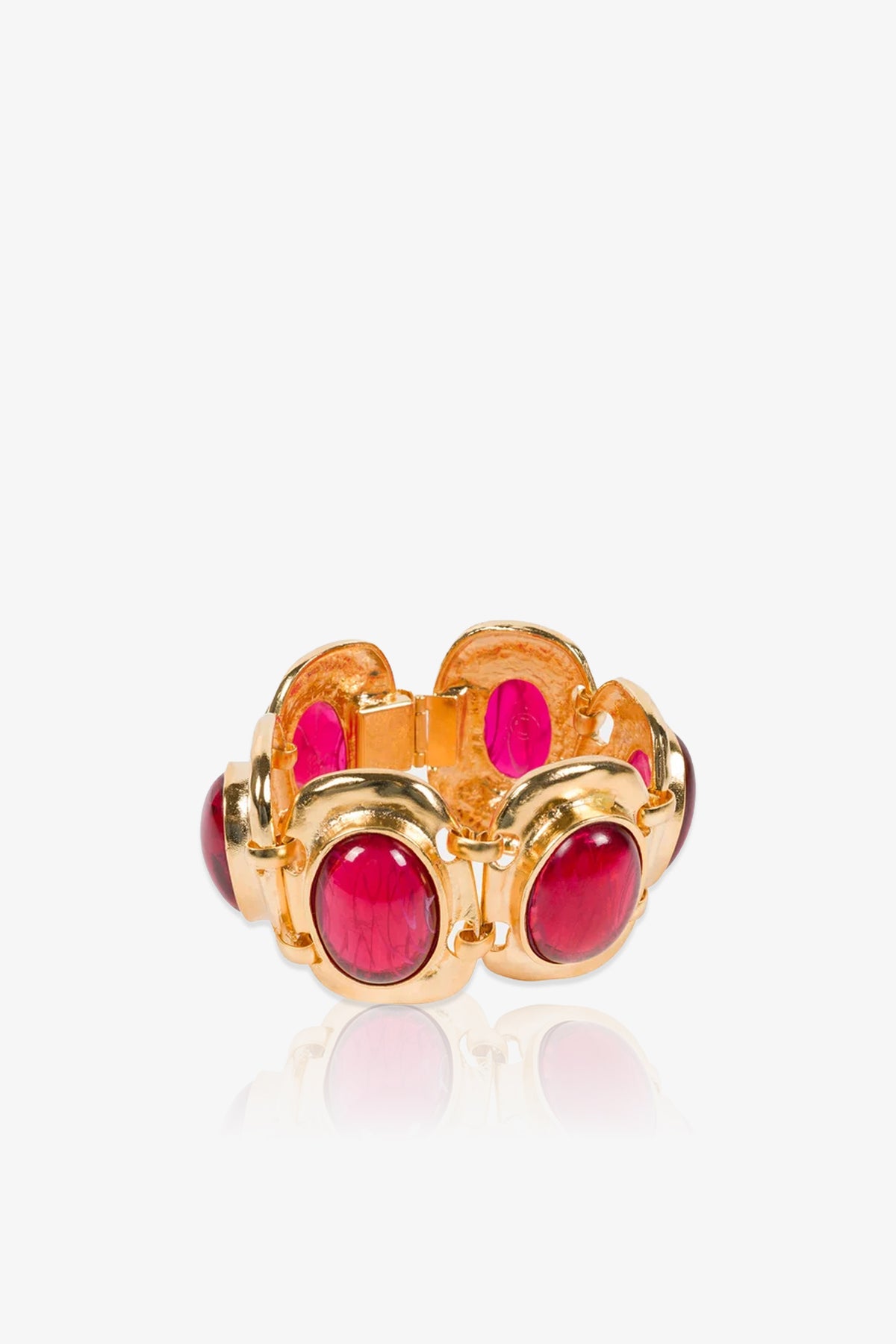 A gold bracelet with an open design, featuring multiple oval-shaped, deep pink ruby cabochons set around the band, displayed against a white background.